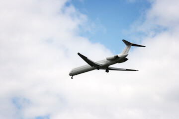 The plane is flying in the sky. Airplane against the background of blue sky and white clouds.