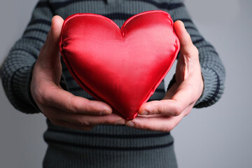 young guy in jacket holding a red heart model in his hand, a symbol of love, concept of confession,...