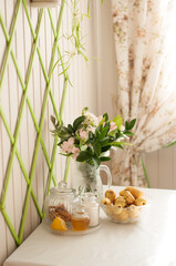 on the bright kitchen table there is a vase with flowers and a vase with pears in a vertical format