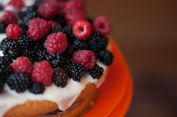 homemade cake with raspberries and blackberries on top, with a blurred background