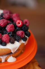 homemade cake with raspberries and blackberries on top, with a blurred background, in a vertical format