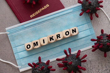 the word omikron on cubes with face mask and passport and corona virus models. Omikron is the new...