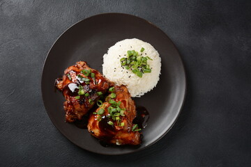 Chicken thighs marinated and cooked in adobo sauce. National filipino dish. Adobo with rice close-up on a plate.