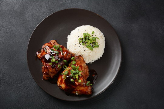 Chicken thighs marinated and cooked in adobo sauce. National filipino dish. Adobo with rice close-up on a plate.