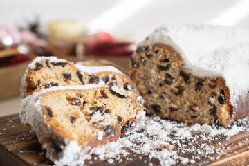 Traditional Christmas stollen made of dried fruits and nuts sprinkled with powdered sugar on the background of a Christmas decor with candles. Traditional Christmas cupcake