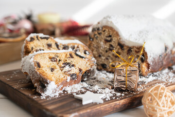 Traditional Christmas stollen made of dried fruits and nuts sprinkled with powdered sugar on the background of a Christmas decor with candles. Traditional Christmas cupcake