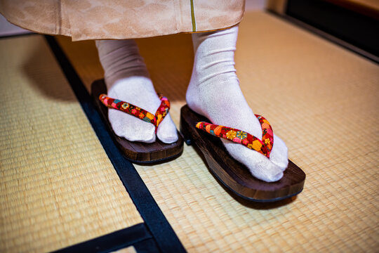Traditional Japanese ryokan house home with tatami mat floor and closeup of woman in kimono and geta shoes tabi socks walking inside