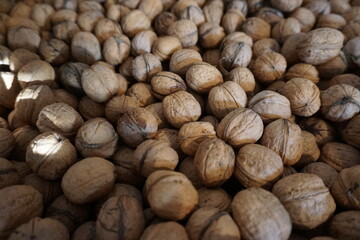 Zbliżenie licznych orzechów włoskich (Juglans regia) rozsypanych na powierzchni, naturalna tekstura, brązowe skorupki. Koncepcja: zdrowa żywność, przekąska, kuchnia, dieta, orzechy ekologiczne.