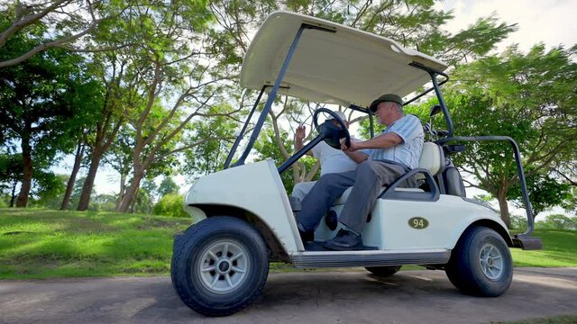 Group of Asian people businessman and senior CEO enjoy outdoor activity lifestyle sport golfing together at golf country club. Healthy men golfer driving golf cart on golf course in summer sunny day
