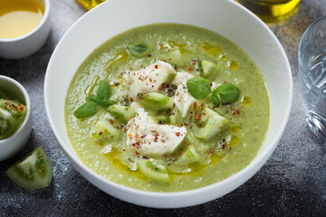 Gazpacho soup made of green tomatoes and served with mozzarella cheese in a white bowl, middle closeup, studio shot