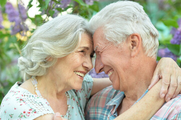 Beautiful senior couple hugging on a lilac background in the park