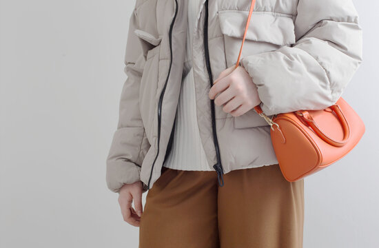 woman in  short down jacket with an orange handbag