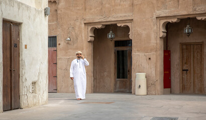 Arab Man walking in al seef district in dubai and talking in the phone