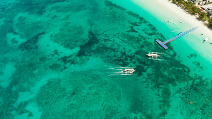 Tourist boats on the surface of the turquoise lagoon, aerial view. Seascape with beach on tropical island. Summer and travel vacation concept. Boracay Island, Philippines