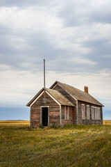 An old abandoned one room school house on the prairie of North Dakota in the evening.