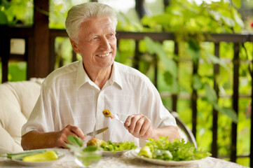 Handsome senior man eating healthy breakfast outdoors