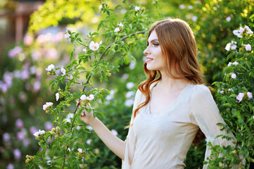 beautiful young woman posing by rose bush