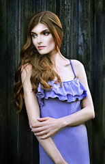 Beautiful young woman posing near the wooden wall