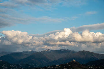 Huge, white clouds over the mountains. Panorama of mountains, hills of the city of Batumi from a bird's eye view. Day. Georgia. Sunny