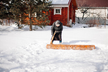 Russian tradition of carpet cleaning. Caucasian elderly woman cleans carpet with fresh snow with...