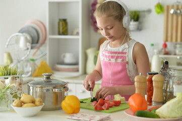 Cute happy girl coocking on  kitchen and listening to music