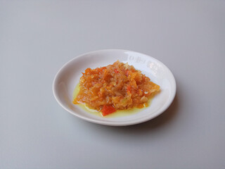 Sambal matang or traditional chili sauce from Indonesia, roughly crushed and cooked by hot oil. Placed in a white small plate.