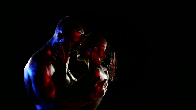 attractive bodies of young man and woman in darkness, embrace of sexy lovers and caress
