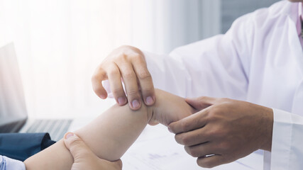 Orthopaedic doctor doing physical examination patient with wrist pain at the clinic. Physical...