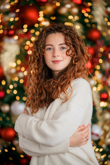 A beautiful girl portrait in a Christmas interior. Christmas tree, decorated fireplace, lots of gifts, Christmas theme. Cozy atmosphere.