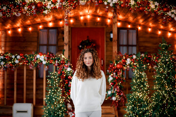 A beautiful girl portrait in a Christmas interior. Christmas tree, decorated fireplace, lots of gifts, Christmas theme. Cozy atmosphere.