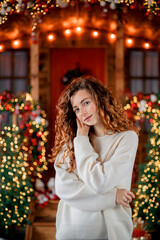 A beautiful girl portrait in a Christmas interior. Christmas tree, decorated fireplace, lots of gifts, Christmas theme. Cozy atmosphere.