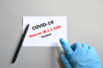doctor hand with blue glove with white card and text Covid-19 Omicron Variant and pen. Medical and...