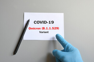 doctor hand with blue glove with white card and text Covid-19 Omicron Variant and pen. Medical and...