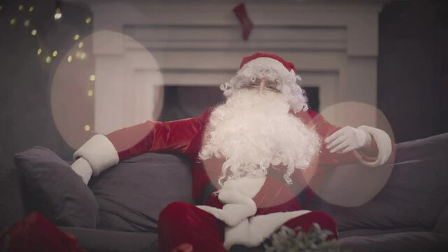 Santa Claus relaxing on couch and touching his beard. Real time