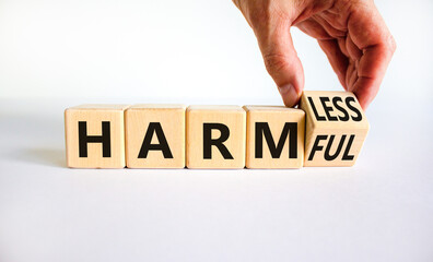 From harmful to harmless. Businessman turns the wooden cube and changes word harmful to harmless....