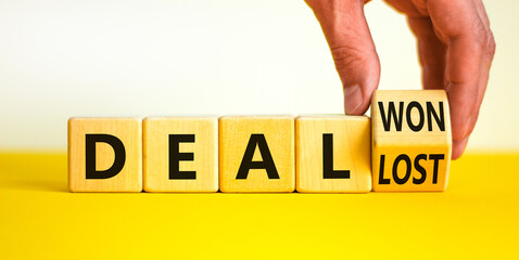 Deal lost or won symbol. Businessman turns a wooden cube and changes words deal lost to deal won. Beautiful yellow table, white background, copy space. Business and deal lost or won concept.