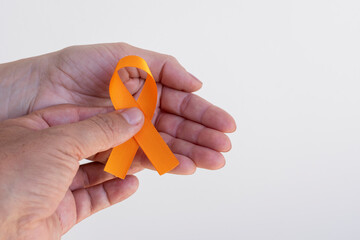 man handing orange ribbon to woman. campaign to prevent skin cancer, melanoma, December orange