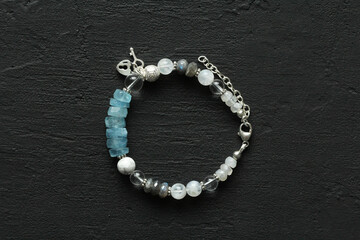 Beautiful asymmetrical designer bracelet made of natural stones and silver. Aquamarine, rock crystal, cacholong, larimar, moonstone. Handmade jewelry made from natural stones on black background
