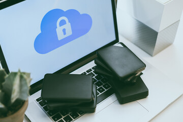 Laptop on the desk with network attached storage. Computer, nas and stack of hard drives on the table. Cloud technology, online disk, remote backup, security copy and archiving internet concept.