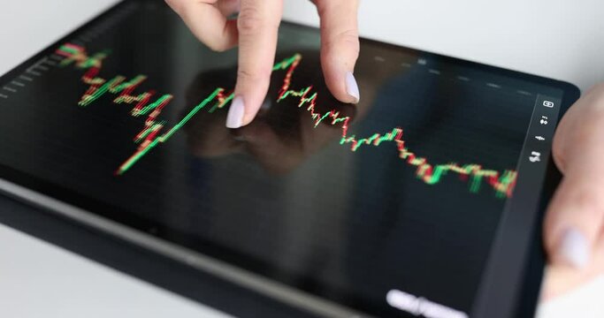 In women hands tablet with pattern of red and green candlesticks at stock exchange auctions