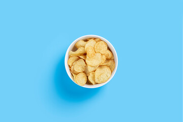 Potato chips in a bowl on a blue background. Top view, flat lay.