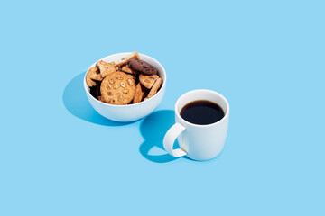 Cup of coffee, cookies in a bowl on a blue background.