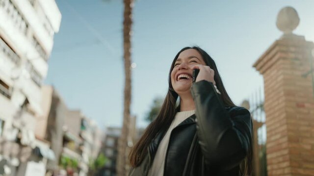 Young hispanic woman smiling confident talking on the smartphone at street