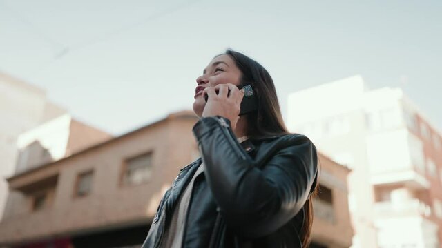 Young hispanic woman smiling confident talking on the smartphone at street