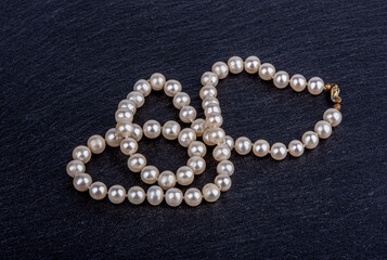 A necklace of pearl beads on a stone surface.