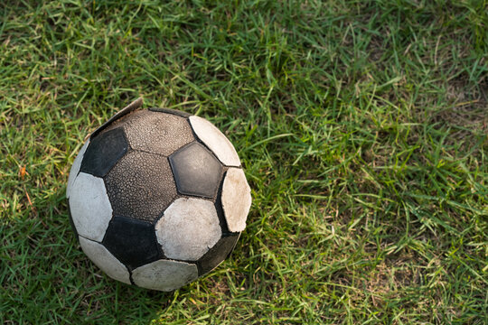 old soccer ball placed on  green grass by top view