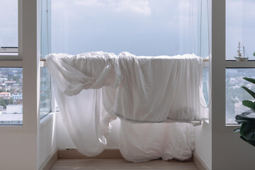 White Bed sheets and duvet clothes hanging on the balcony to dry in apartment.