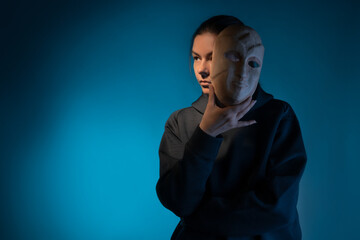 Remove the mask, reveal the identity, express yourself in something, the concept. A young woman in a black hoodie holds a mask in her hands, removing it from her face.