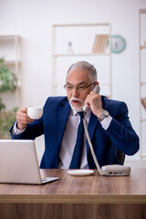 Old male employee drinking coffee during break