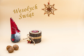 Obrazy na Plexi  Pocztówka świąteczna z napisem Wesołych Świąt i beżowym tłem, orzechami, drewnianą świeczką i zabawnym skrzatem